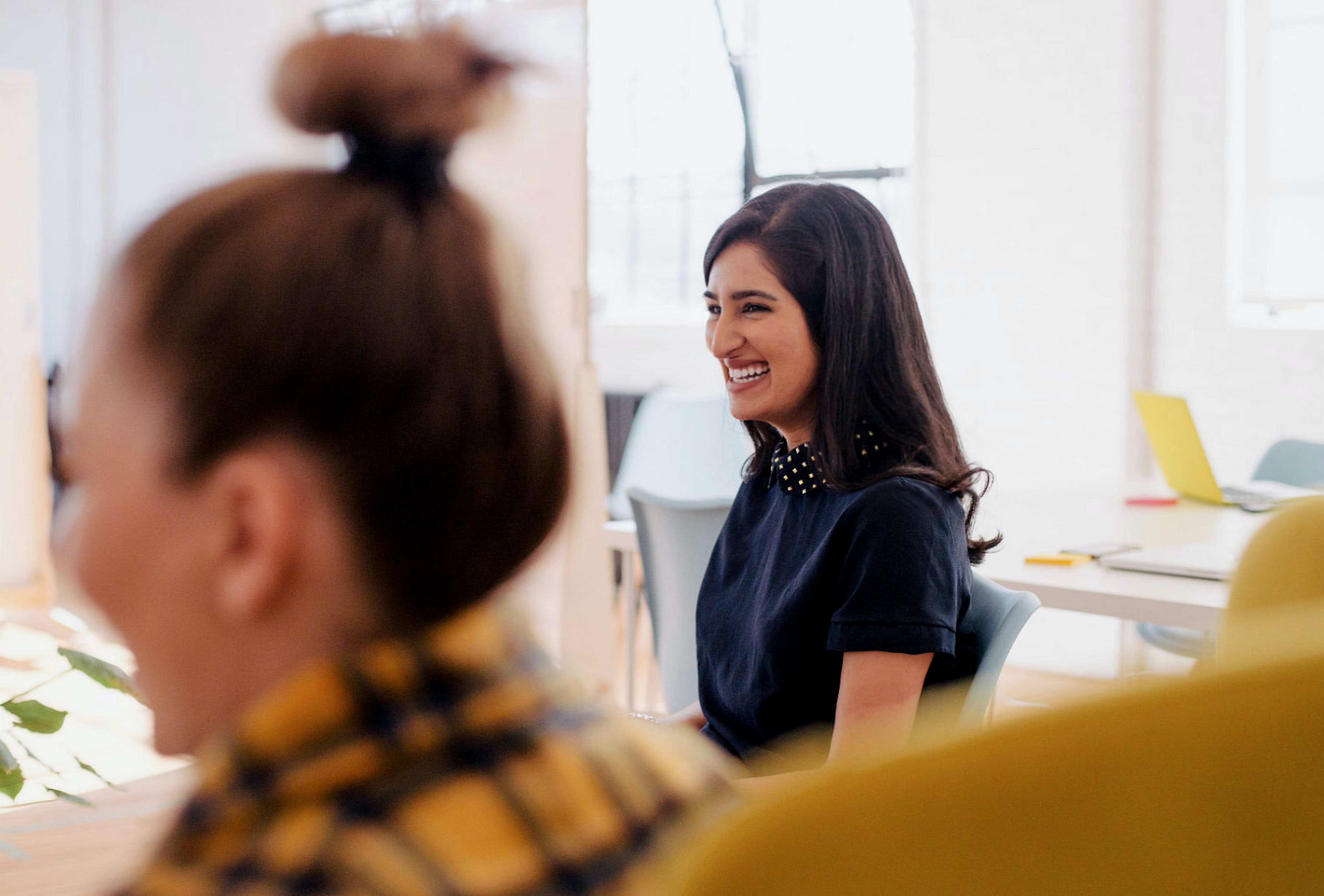 A woman in an office setting smiling to something out of view.