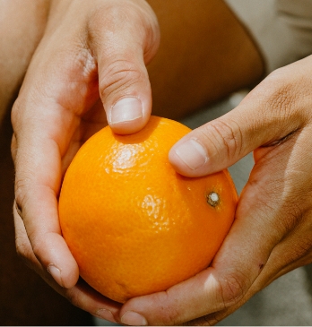 Image of a person holding an orange.