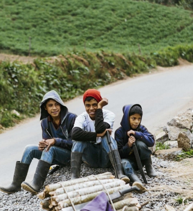 Three people sitting by a river.